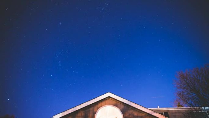 星星在房屋上空的蓝色夜空中移动