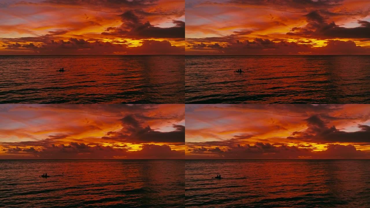 令人惊叹的美丽空中无人机图像，描绘了海洋上空的红色热带日落，两名男子在独木舟上钓鱼