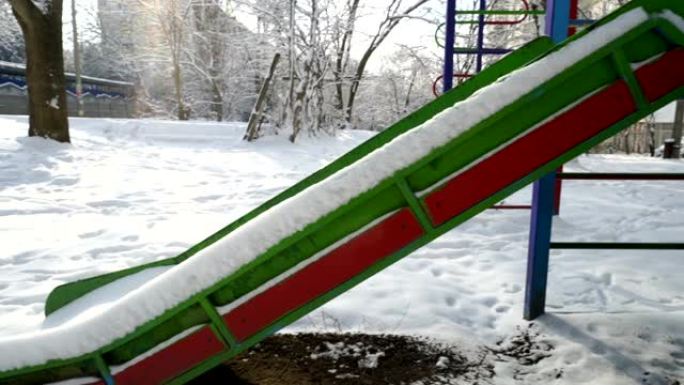 冬天空荡荡的儿童游乐场。白雪覆盖的儿童滑梯。