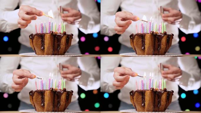 装满五颜六色蜡烛的生日巧克力蛋糕。男子在生日聚会上点燃蜡烛