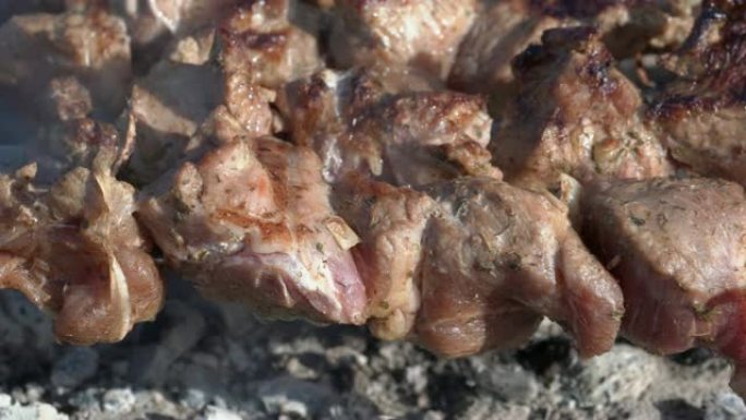 烤开胃多汁猪肉烧烤在木炭烤架上的金属串上烹饪，带火烟