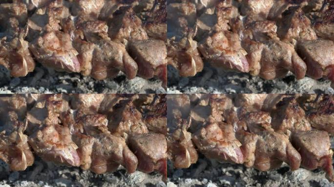 烤开胃多汁猪肉烧烤在木炭烤架上的金属串上烹饪，带火烟
