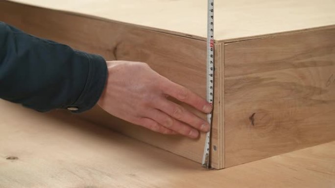 男子手持柔性尺子测量木箱高度的特写镜头