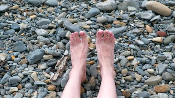 女人的脚在石头海滩靠海。