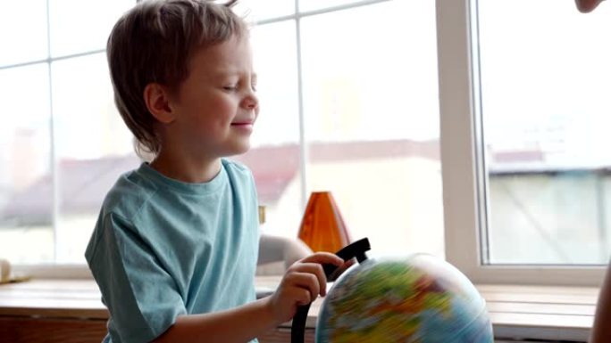 一位迷人的白种人母亲用地球仪向她的小儿子展示世界各国。