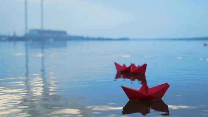 幼稚的纸船漂浮在模糊的背景上的水面上。