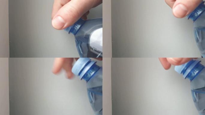 双手打开一瓶新鲜矿泉水全高清视频。抽象光背景上的塑料瓶特写。