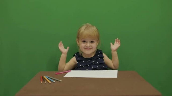 女孩在桌子上画画。快乐的三岁女孩。可爱的女孩微笑着。棕色的眼睛。漂亮的小孩，3-4岁的金发女孩。做鬼