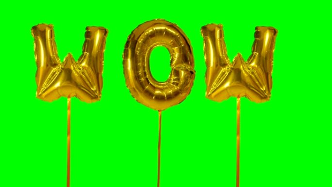 来自漂浮在绿色屏幕上的氦气金色气球字母的wow单词
