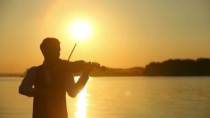 小提琴家男人在日落时演奏小提琴