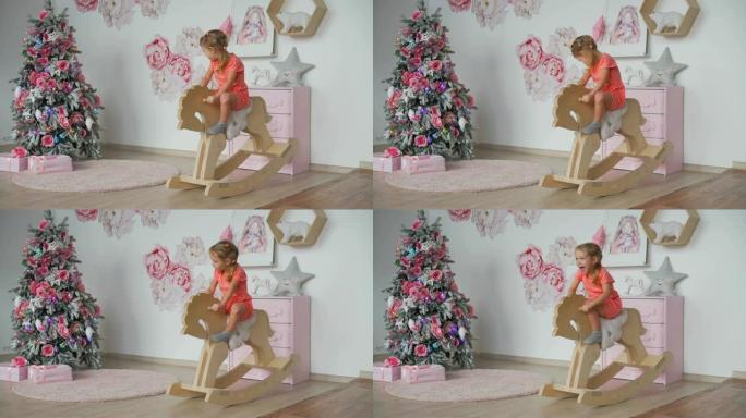 女孩骑玩具摇马在圣诞树附近