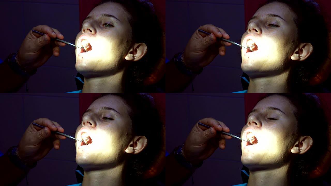牙医的小女孩用牙镜检查牙齿