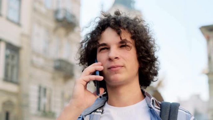 年轻人在智能手机上聊天的特写肖像。在市中心，在外面用手机的快乐年轻休闲小伙子。一个英俊的潮人在电话里