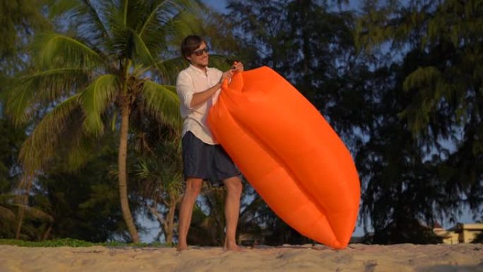 一个年轻人的慢镜头在美丽的海滩上充气沙发
