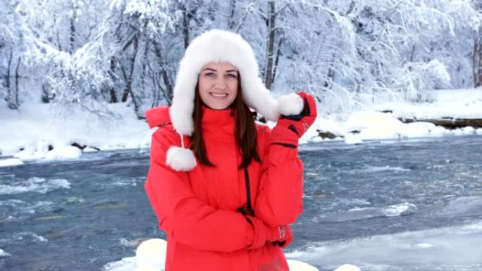 冬天河附近的一位穿着红色外套的女人享受着一个寒冷的早晨，把雪扔在自己身上，从幸福中旋转。
