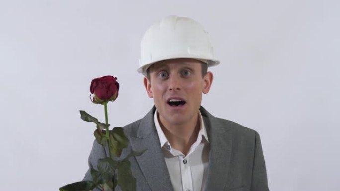 戴着头盔的真正害羞男人的肖像向前伸出一只手，手里拿着红玫瑰。
