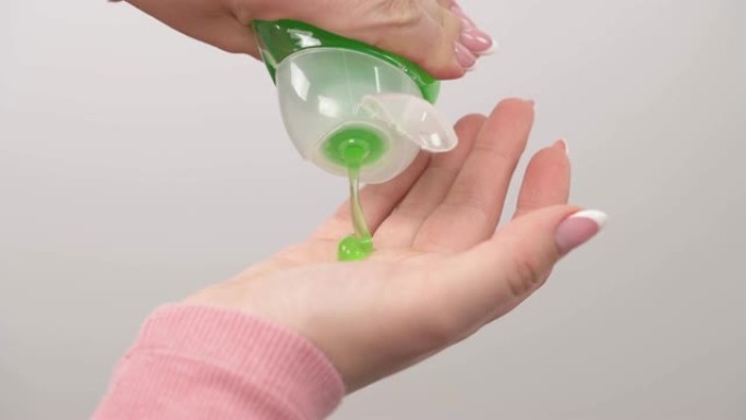 将绿色液体洗发水从瓶子倒入手中的特写镜头