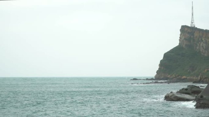 在雾天，海浪撞击多岩石的海岸和山崖的4k景观稳定镜头。海浪溅到石头上，溪流猛烈地流过岩石。