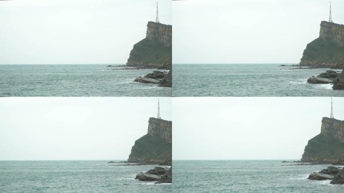 在雾天，海浪撞击多岩石的海岸和山崖的4k景观稳定镜头。海浪溅到石头上，溪流猛烈地流过岩石。