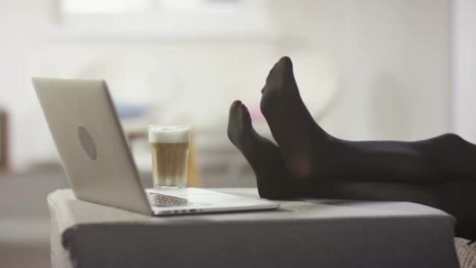 穿着长统袜的白人女性在沙发上放松疲惫的脚