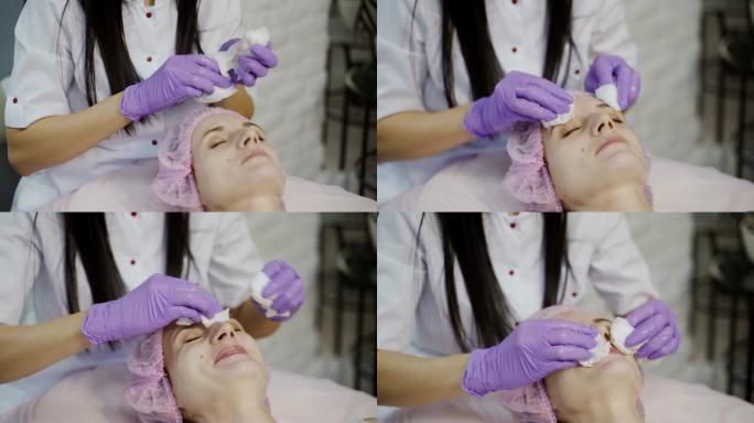 年轻美丽的女人接受面部按摩和水疗治疗。