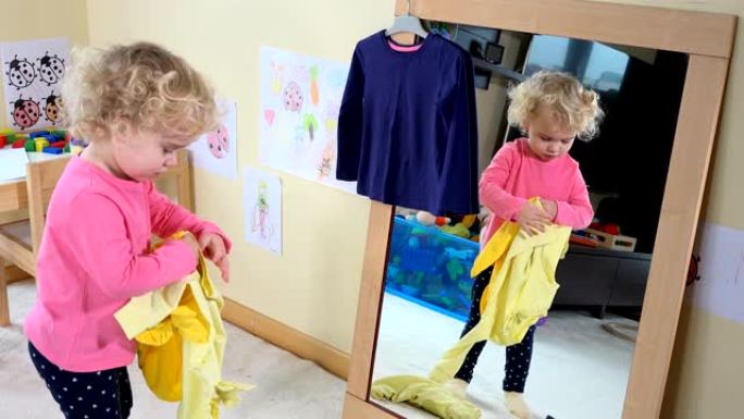 可爱的女孩在家对着镜子量衣服