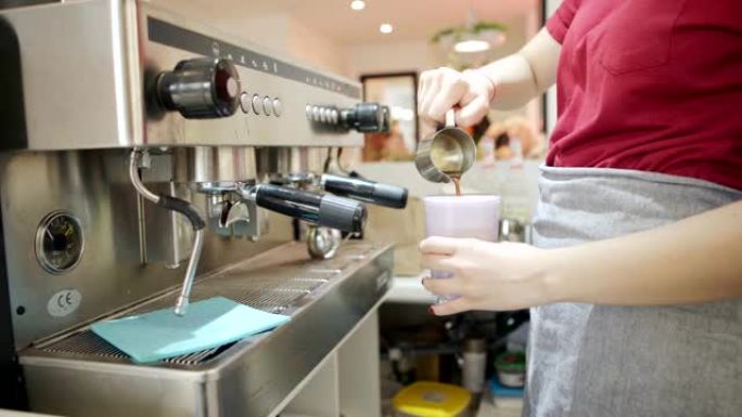 无法识别的女调酒师在咖啡馆工作时，将刚煮好的咖啡加入一杯美味的饮料中