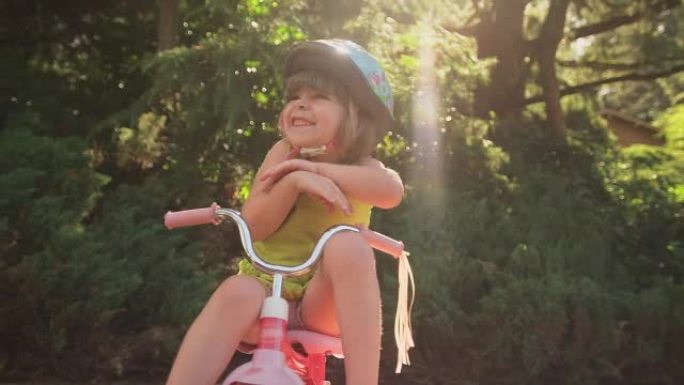 一个可爱的小女孩坐在三轮车上微笑着