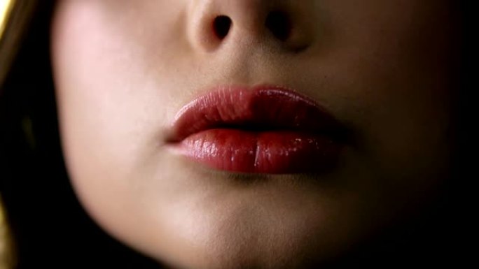 性感光泽嘴唇的极端特写。年轻女子以性感诱人的姿态pur起嘴唇。慢动作。前视图