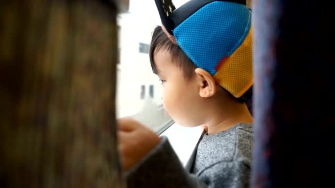 可爱的男孩看着外面的火车窗户。