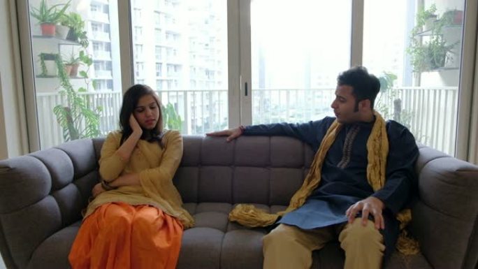 穿着传统印度服装的印度男人和女人坐在一起，进行了认真的交谈，因为男人试图安慰并向她保证