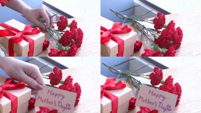 年轻女子系蝴蝶结包装手工制作的精美礼盒母亲节礼物在家用红色康乃馨花束隔离在木桌上，特写特写概念
