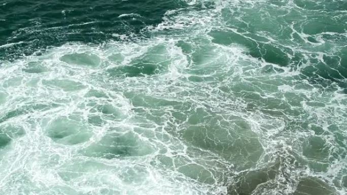 海蓝宝石海浪从船上的工作引擎沸腾并产生泡沫，海鸥在海上飞行