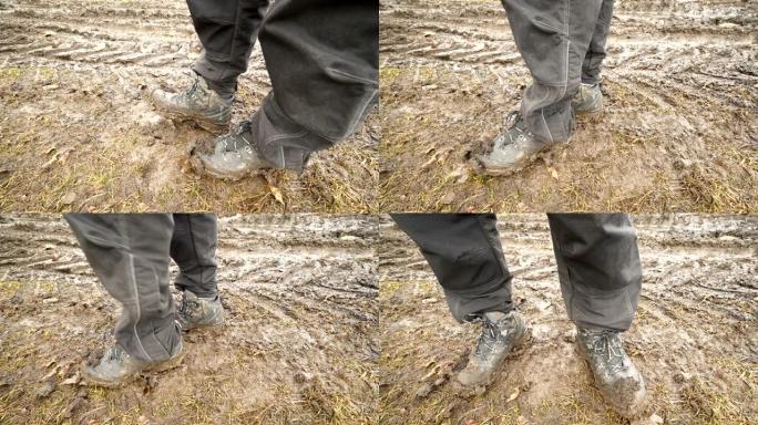 男子徒步旅行者穿着一双泥泞的登山靴在泥泞的轨道上