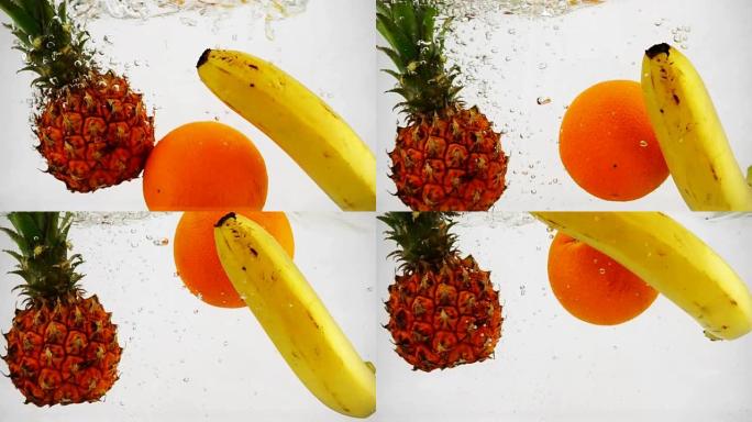 菠萝、橘子和香蕉落到水里，里面有很多小气泡。孤立的白色背景上的水果。