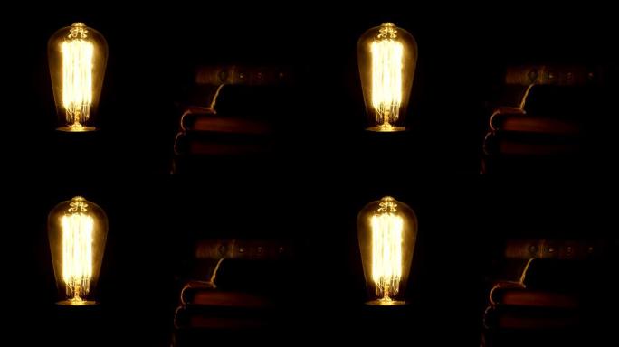 老式灯泡在复古书籍附近的黑暗中打开和关闭。