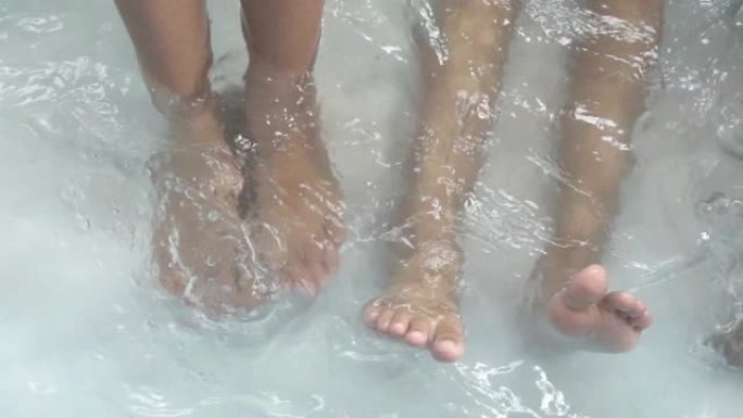 孩子的腿在游泳池里泼水