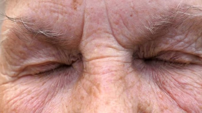老祖母皱着眉头的脸带着悲伤的目光看着镜头。成熟女人的肖像强烈地扭曲了她灰色的眼睛。高级女士的悲伤表情