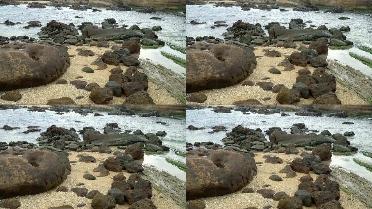 4k缓慢放大拍摄的海浪从海滩撞向岩石海岸。海浪溅到石头上，溪流猛烈流过许多岩石。