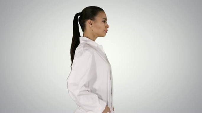 穿着白色礼服外套制服的年轻女药剂师在渐变背景上行走