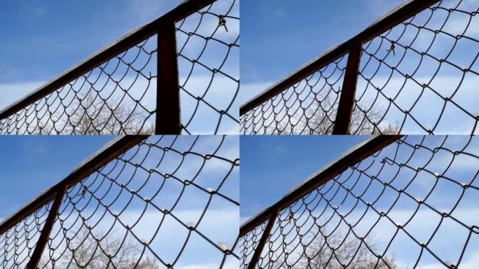 冬天，铁链围栏靠着天空。金属线上的雪融化