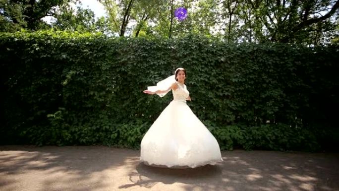 快乐的新娘在公园里旋转。新娘的礼服。婚礼当天。