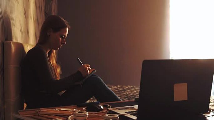 生活方式: 年轻美丽的女孩自由艺术家设计师在日落时在家中的kraftpaper上素描和绘画。中拍，静