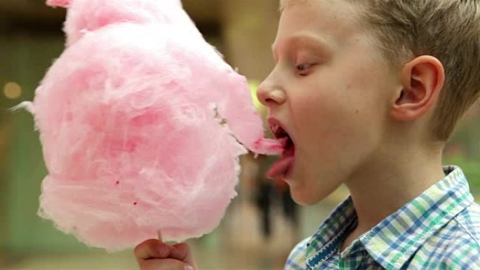 一个男孩吃粉红色棉花糖的慢动作视频