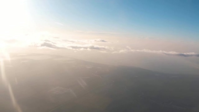从飞机的窗户上看地面，太阳和云。