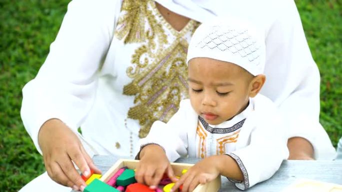 从正面看高角度: 穆斯林儿子玩木制玩具，母亲亲吻他