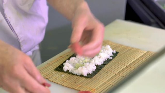 男性手触摸米饭。紫菜上的白米。寿司的基本原料。日本餐厅的厨房。
