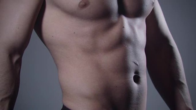 灰色背景上肌肉发达的男性身体的特写。
