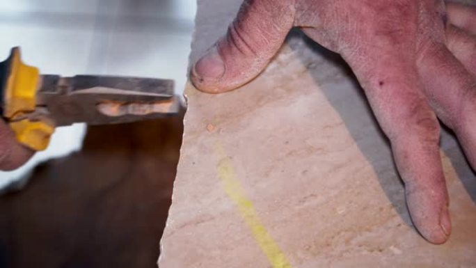 Tiler使用钳子并折断瓷砖的边缘