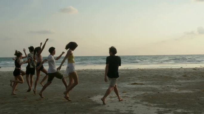一群朋友在日落背景下沿着海滩奔跑。